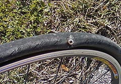 a bike tire with a large screw through the sidewall